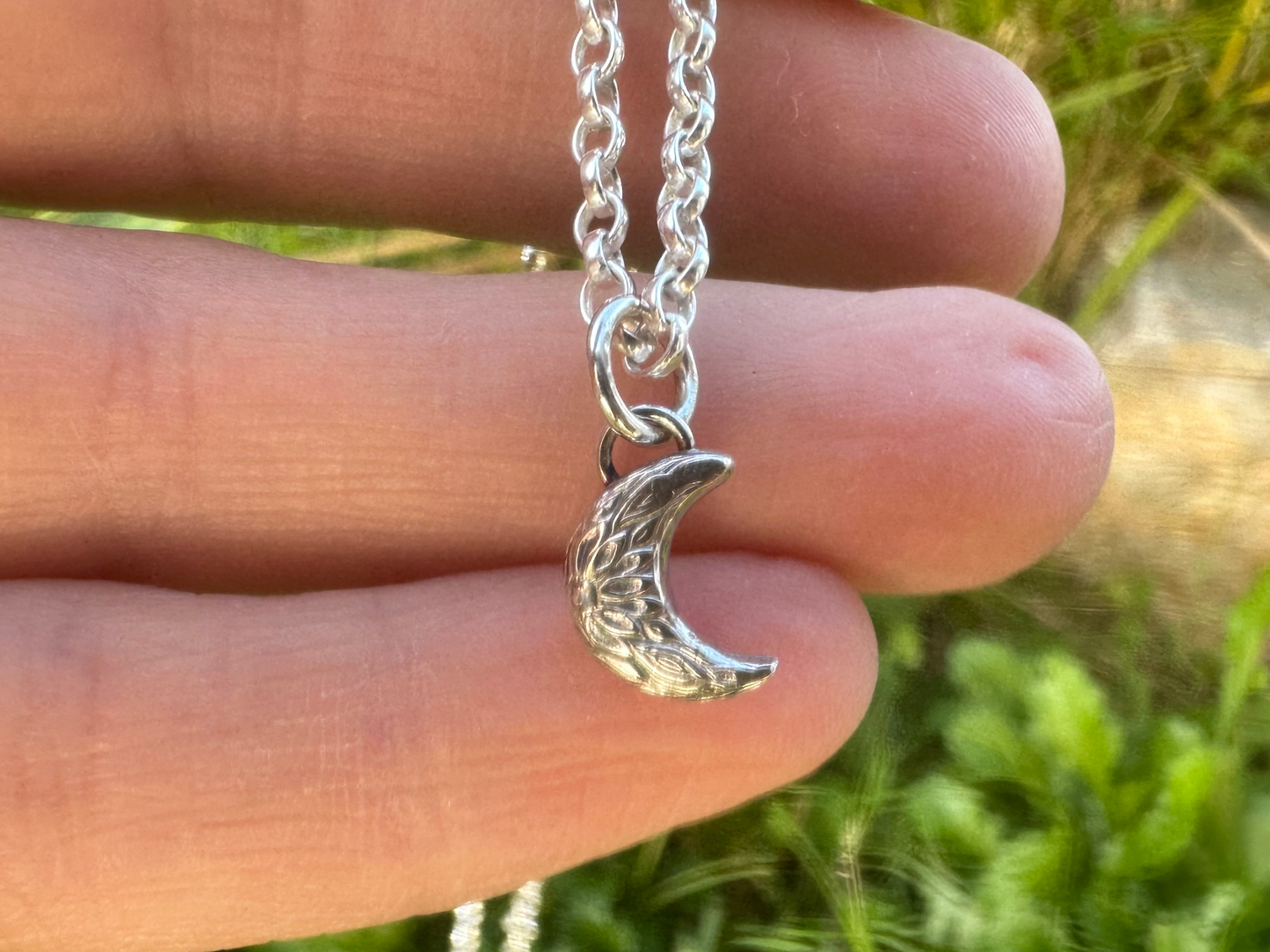 Handmade rustic crescent moon charm on hand